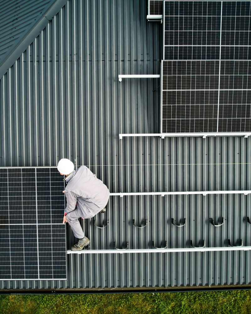 Men workers installing solar panels on roof of house.